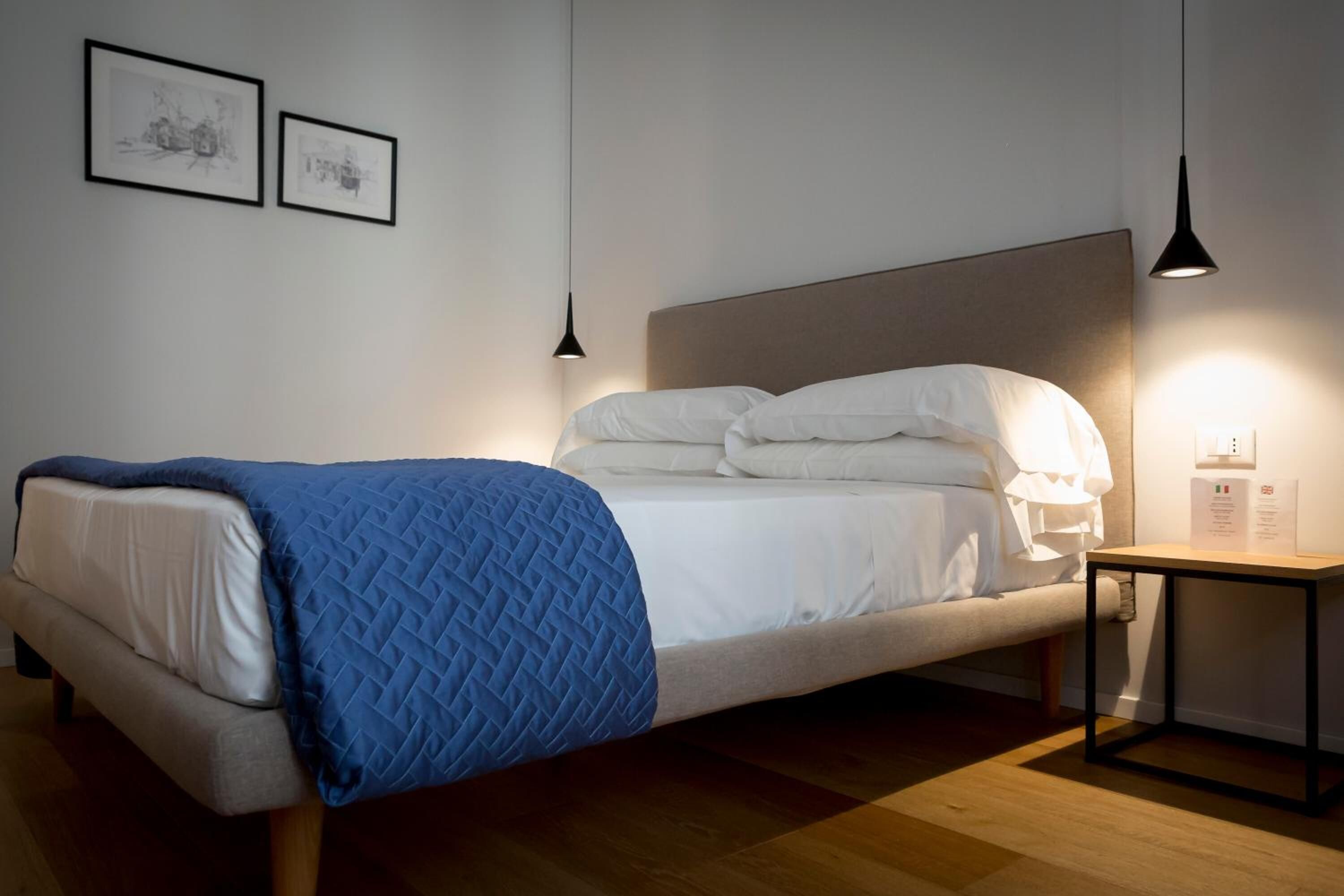A modern bedroom with a bed, a bedside table, and two wall-mounted pendant lights.