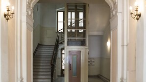 A grand hallway with a staircase, ornate columns, and wall sconces. - Trieste 411 e Trieste 411 II (Rooms & Apartments) (Trieste)