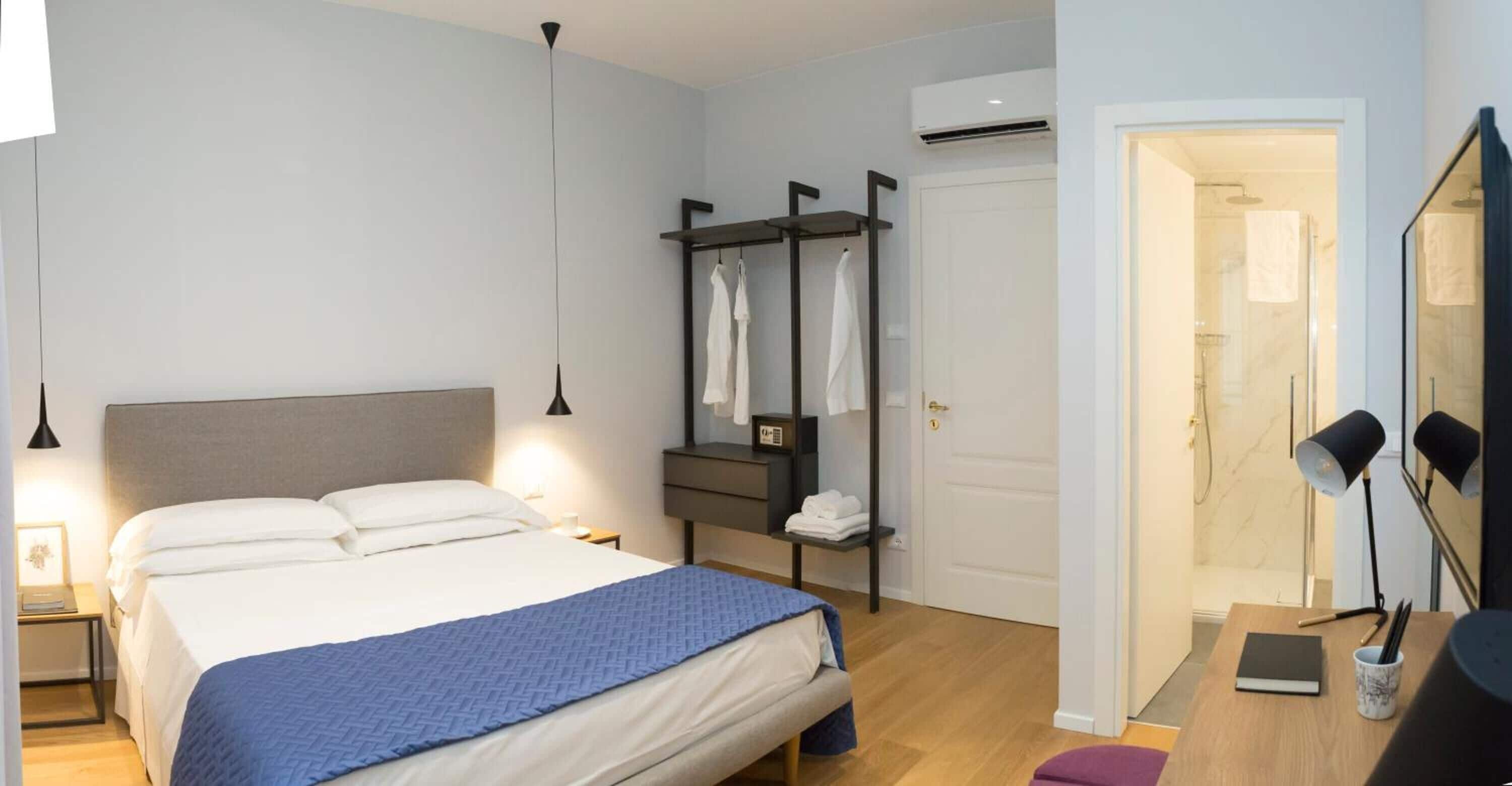 Ein modernes Schlafzimmer mit Bett, Nachttischen, einem Kleiderschrank und einem durchgegangenen Tür erkennbaren Badezimmer.
