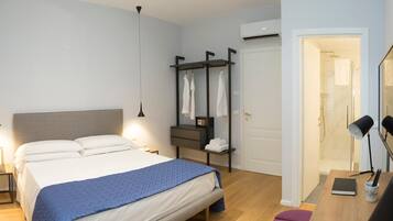 Ein modernes Schlafzimmer mit Bett, Nachttischen, einem Kleiderschrank und einem durchgegangenen Tür erkennbaren Badezimmer.