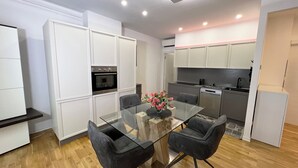 A modern kitchen with white cabinets, a black oven, and a glass dining table with two chairs. - Trieste 411 e Trieste 411 II (Rooms & Apartments) (Trieste)