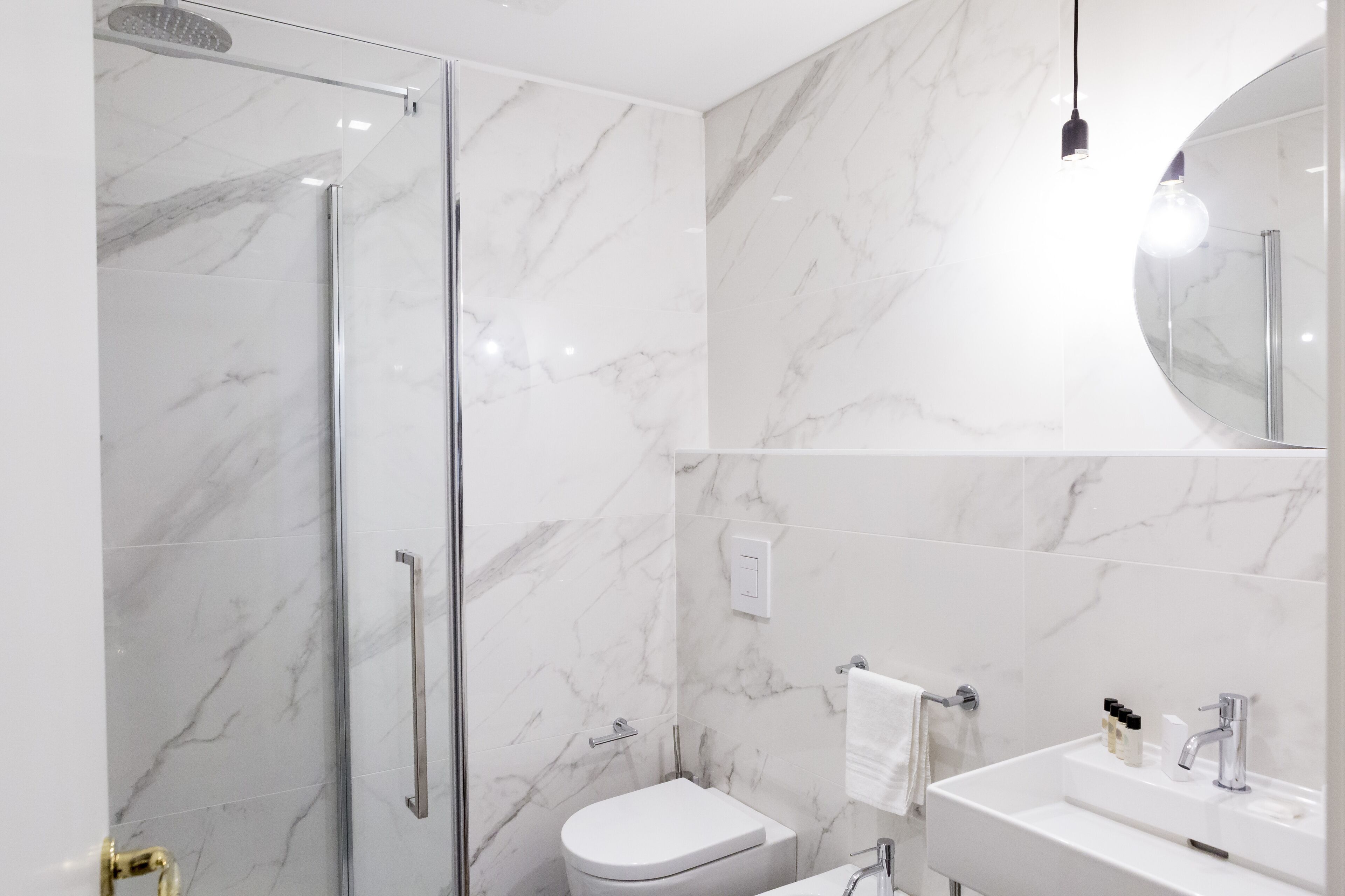 Un baño moderno con cabina de ducha de vidrio, un inodoro blanco y un lavabo con espejo.