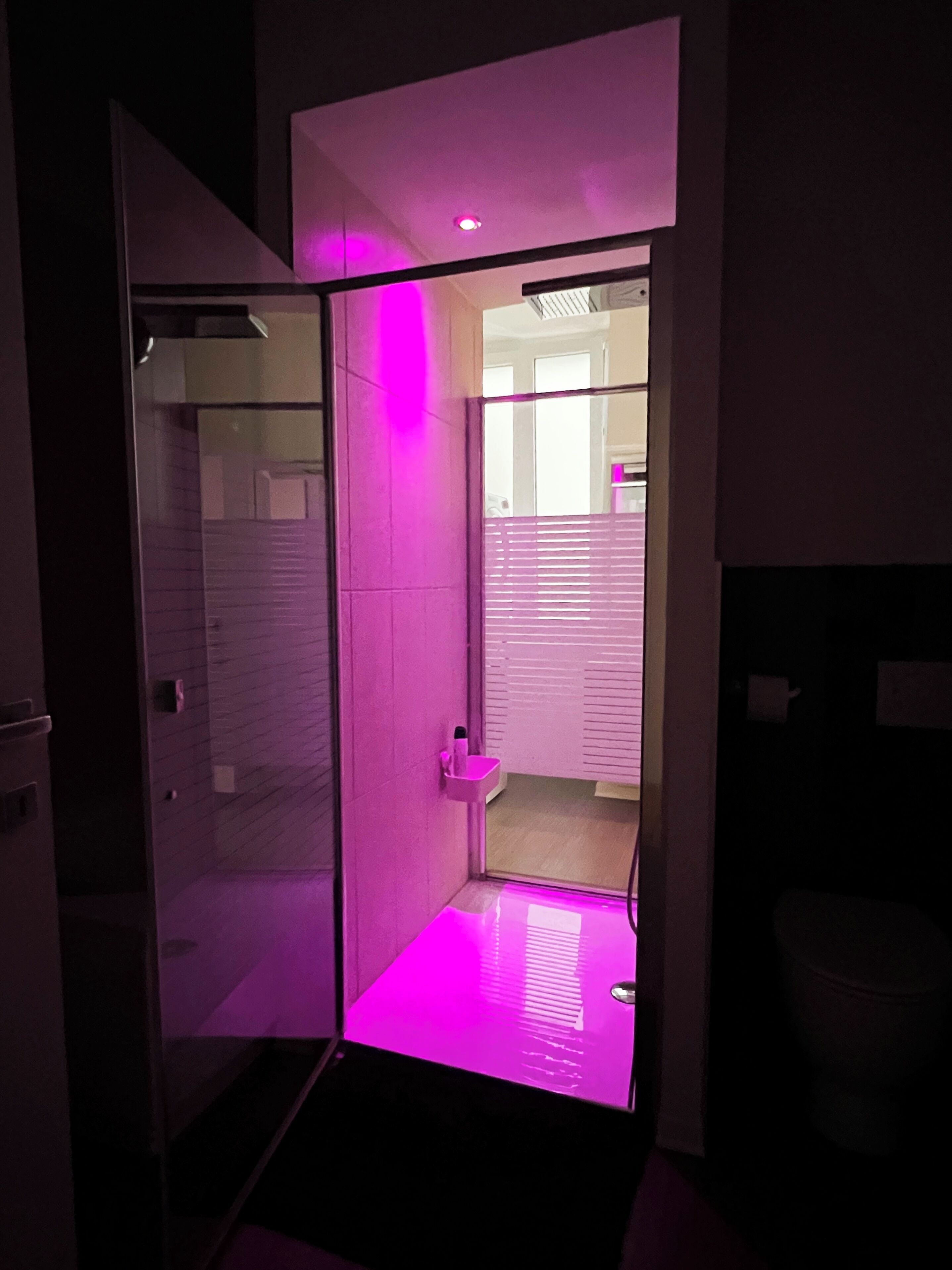 Une salle de bain moderne avec une douche à parois de verre, un petit lavabo et des toilettes.