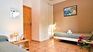 Ein kleines, gemütliches Schlafzimmer mit Bett, Nachttisch, Lampe und einem Bild an der Wand.