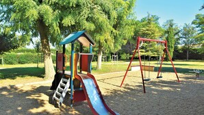 Ein Spielplatz mit Rutsche, Schaukeln und Klettergeräten.