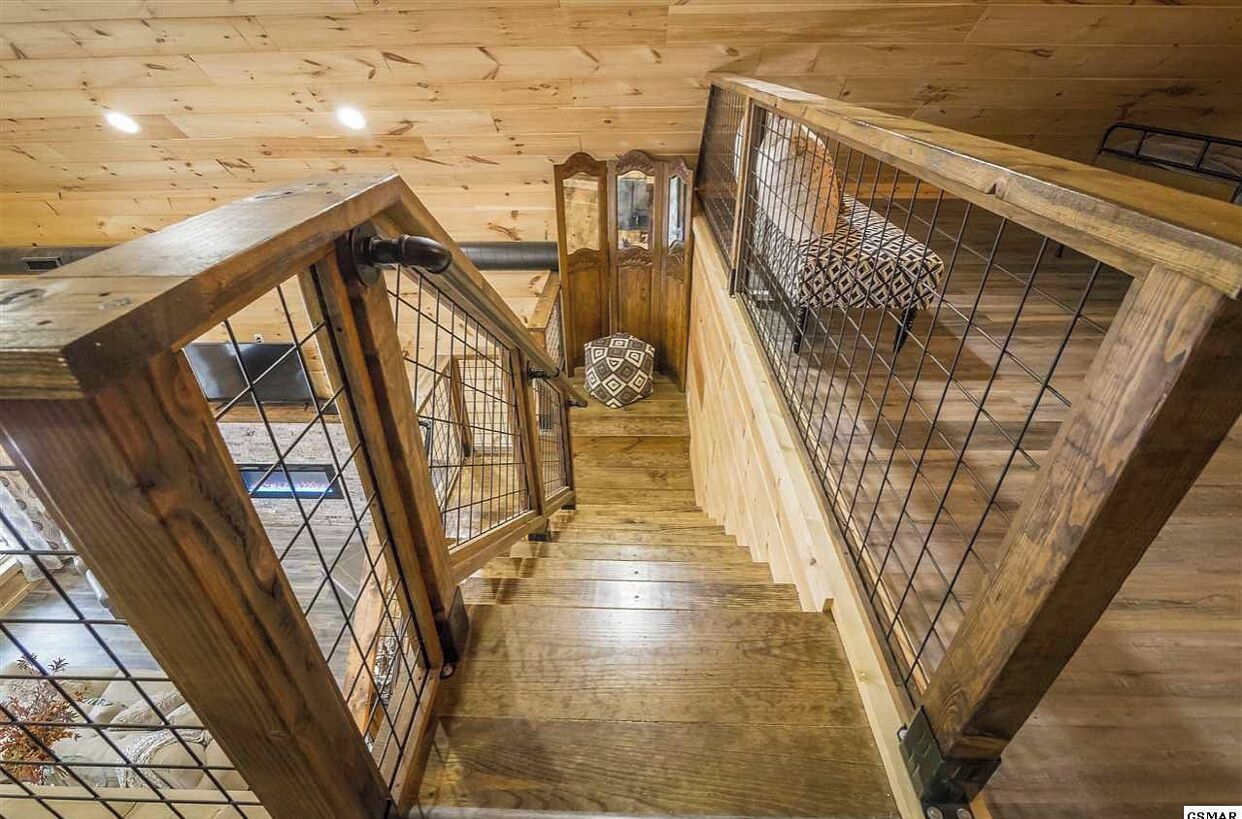A wooden staircase with a metal railing and a patterned cushion at the top.