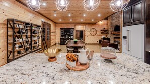 A spacious kitchen with wooden walls, a marble countertop, and modern lighting fixtures. - Boomerang Cabin | Large Family Retreat Near Broken Bow Lake (Broken Bow)