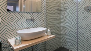 Ein Badezimmer mit einem großen, ovalen Waschbecken, einem Spiegel und einer Dusche mit Glastür.