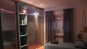 Une chambre avec deux lits, une armoire, un radiateur et une fenêtre avec des rideaux.