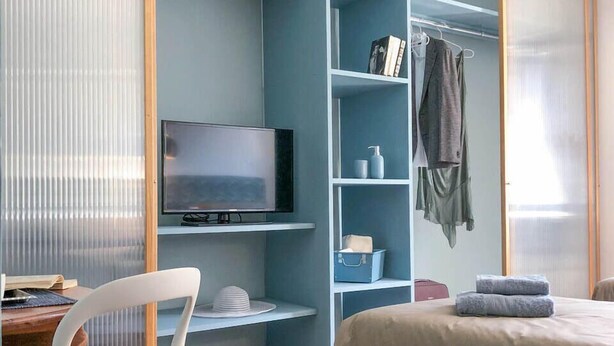 Une chambre à coucher moderne avec un lit, un bureau, une chaise et un téléviseur.