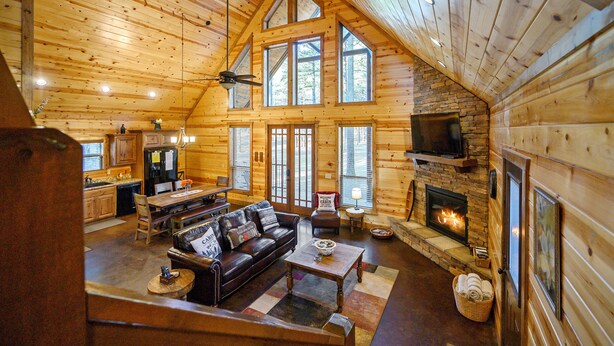 A log cabin interior with a dining area, living room, fireplace, and kitchen. - Bryce’s Crossroad | Family Cabin Near Broken Bow Lake (Broken Bow)