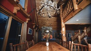 Ein Holzespeisesaal mit Stühlen, einer Chandelüster und einem Steinkamin.