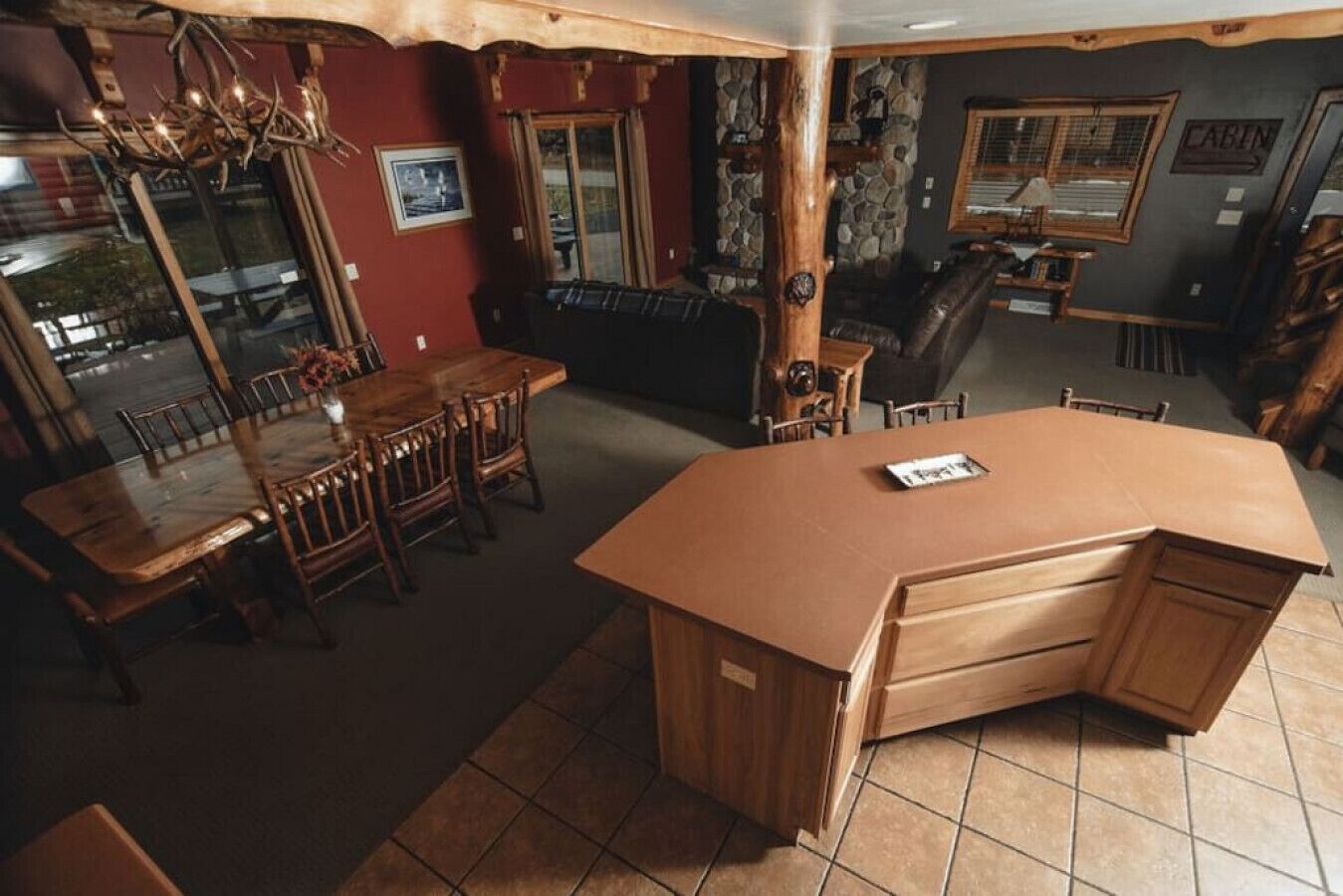 Une cuisine avec un îlot central en bois, une table à manger avec des chaises et un mur en pierre.