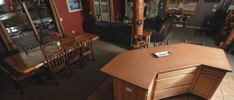 Une cuisine avec un îlot central en bois, une table à manger avec des chaises et un mur en pierre.