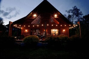 Uma cabana de tronco com varanda, área de estar externa e luzes de fada.