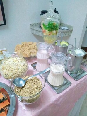 A buffet table with various food items including cereal, yogurt, and a fruit punch. - Hotel Capri (Medianeira)