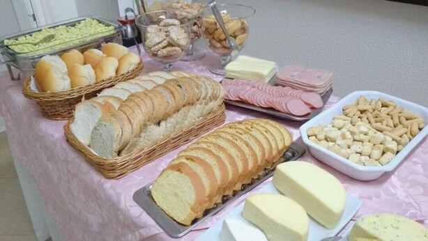 A buffet table with various food items including bread, cheese, and meat. - Hotel Capri (Medianeira)