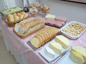 Une table de buffet proposant divers aliments, notamment du pain, du fromage et de la viande.