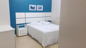 A bedroom with a bed, bedside tables, and a blue accent wall. - Hotel Capri (Medianeira)