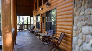 Eine Holzhütte mit Veranda, Steinmauer und Sitzgelegenheit im Freien.
