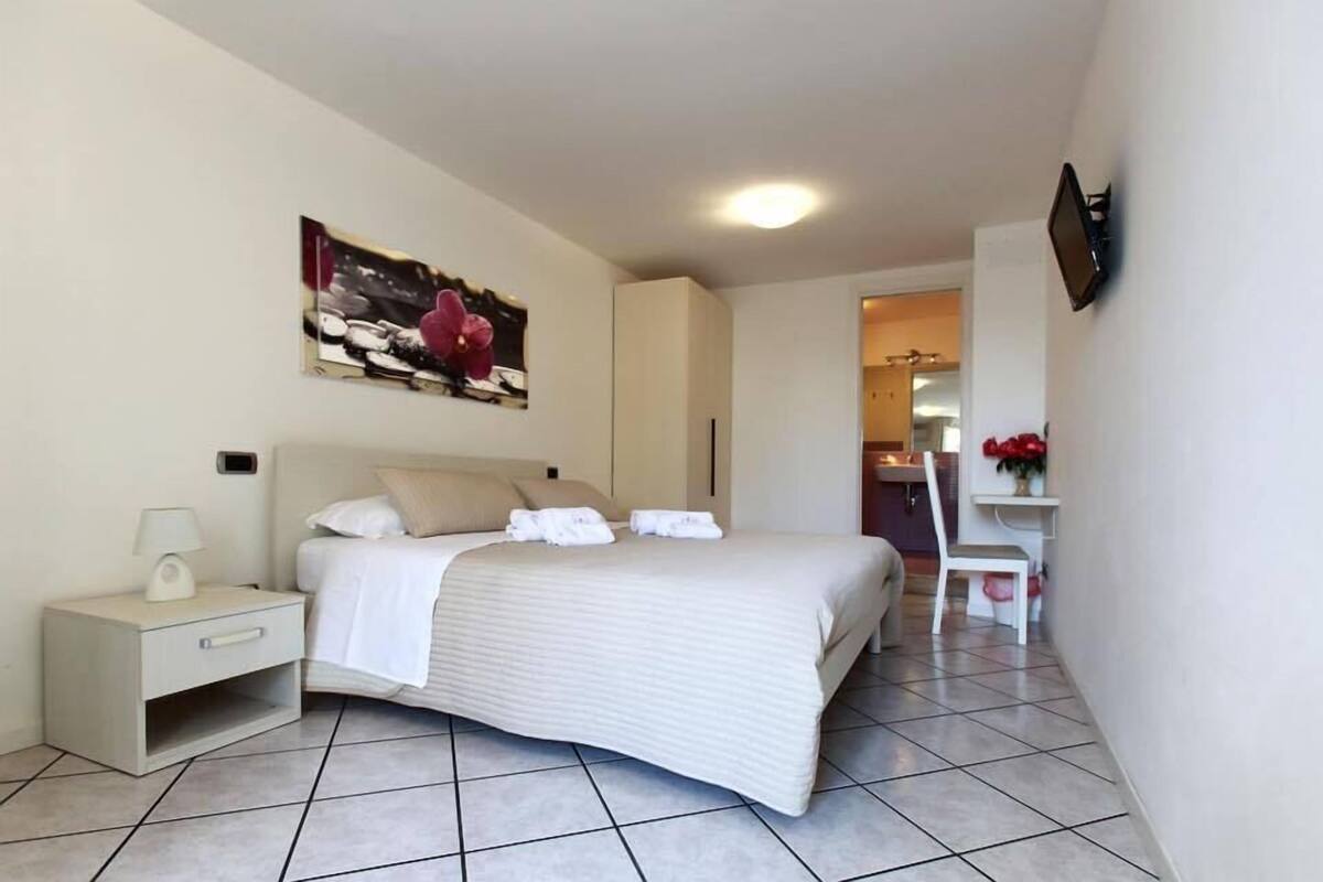 Un dormitorio ordenado con cama, mesita de noche y un cuadro en la pared.