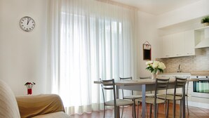 A modern kitchen with white cabinets, a dining table with chairs, and a clock on the wall. - A Casa Di Amici (Giardini Naxos)