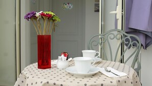 A table with a polka dot tablecloth, a red vase with flowers, white cups and saucers, and a metal chair. - A Casa Di Amici (Giardini Naxos)