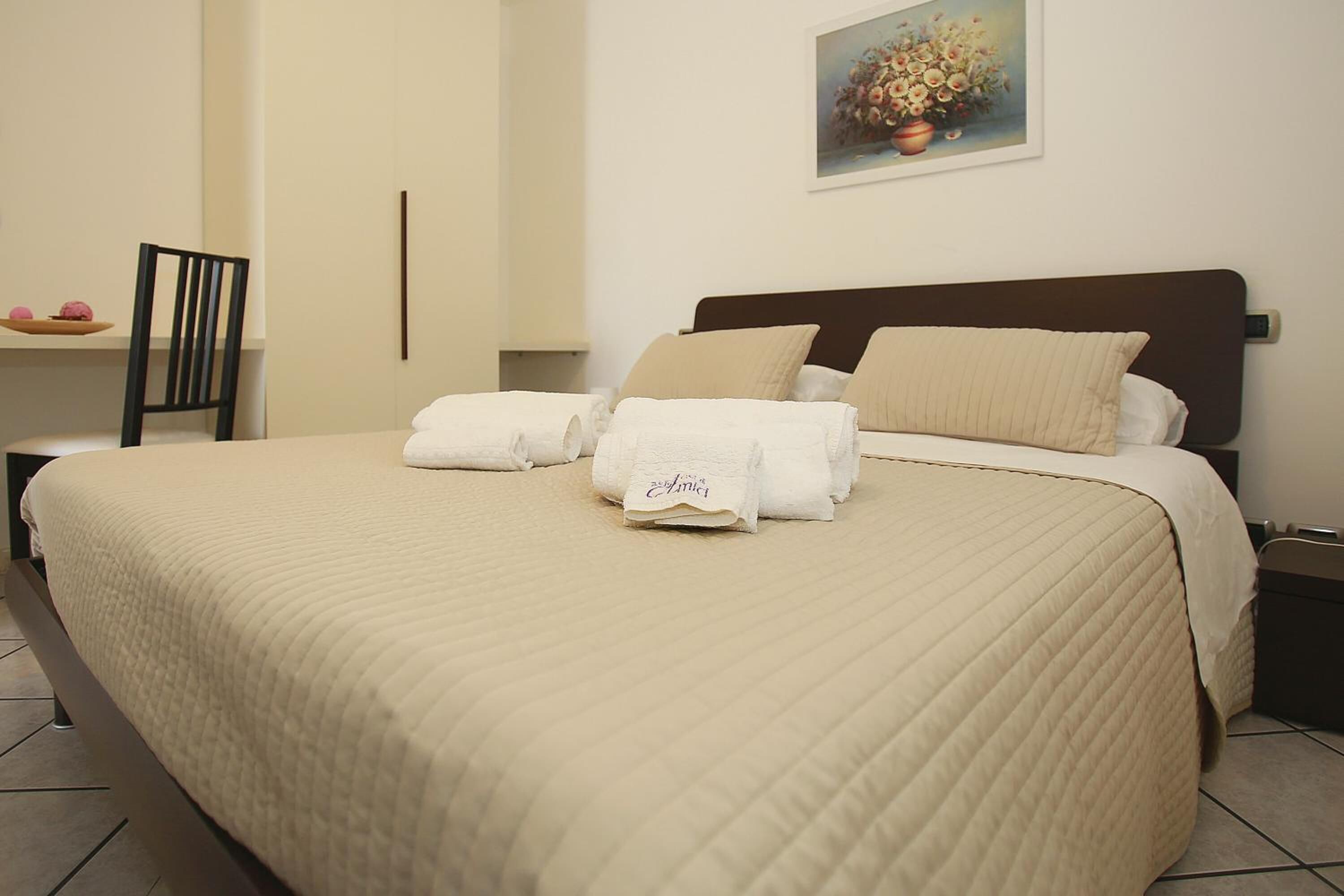Uma cama bem arrumada com um edredom acolchoado, duas almofadas e uma toalha dobrada sobre a cama.
