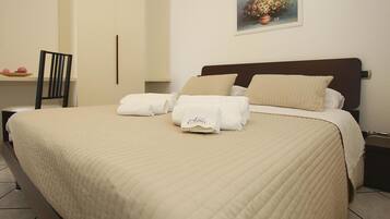 Uma cama bem arrumada com um edredom acolchoado, duas almofadas e uma toalha dobrada sobre a cama.