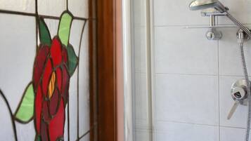 A shower area with a glass door featuring a stained glass flower design.