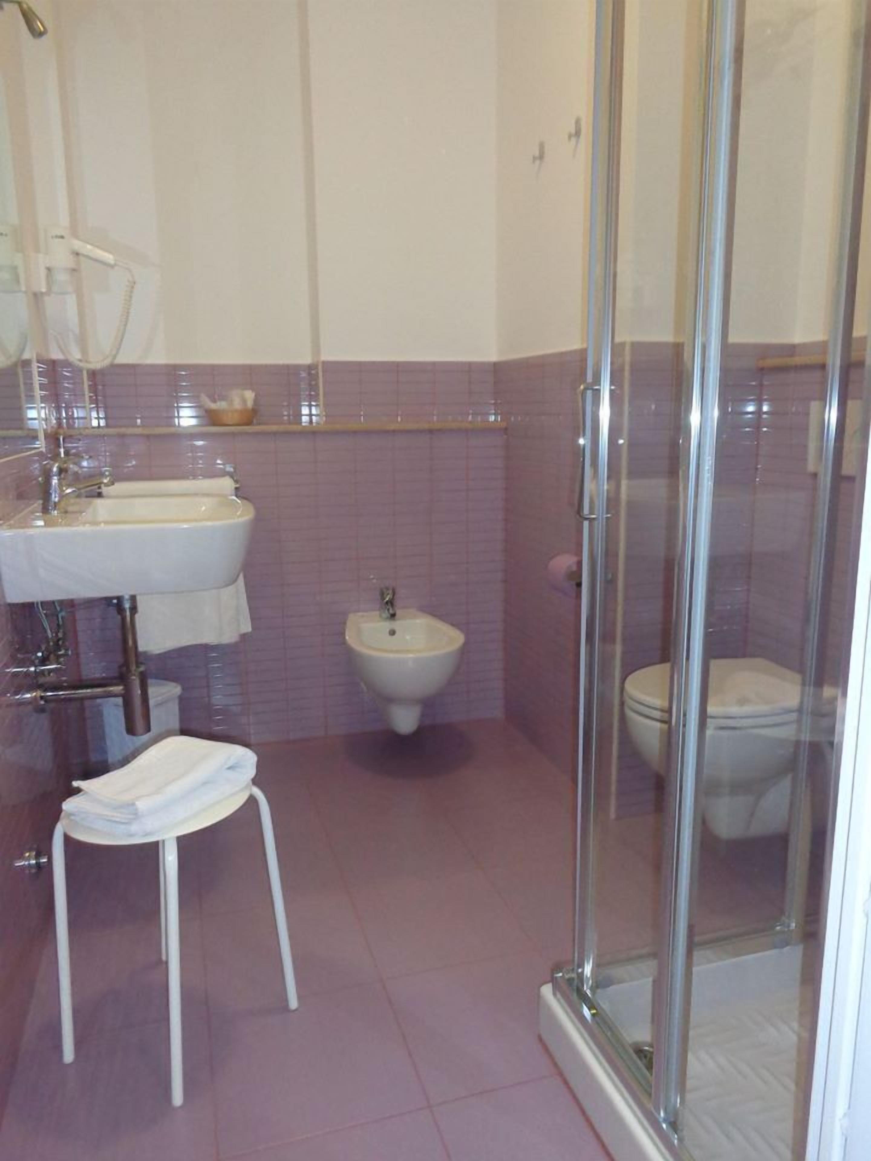 Un baño con ducha, bidé, inodoro y dos lavamanos.