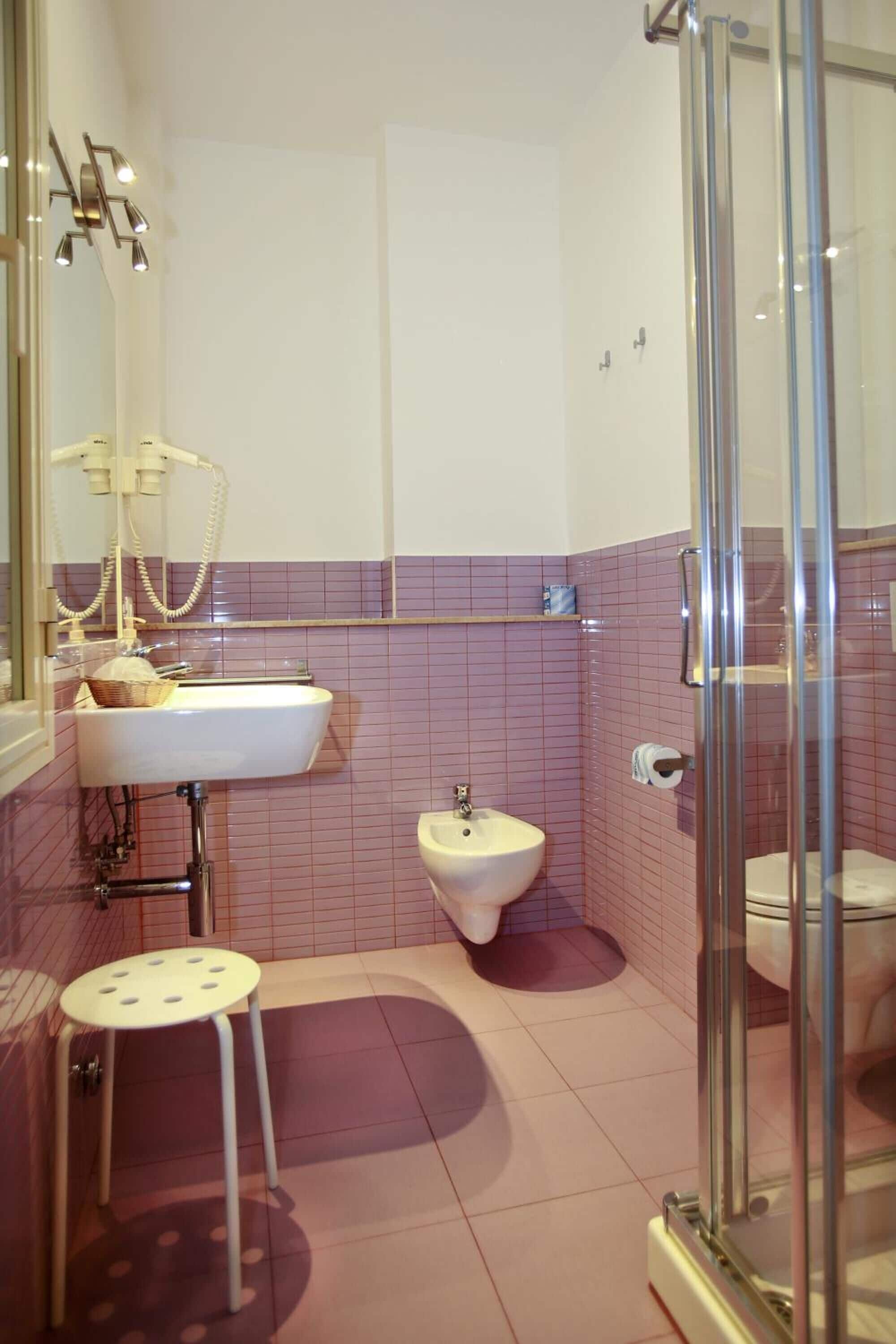 A bathroom with a sink, bidet, toilet, and a glass-enclosed shower.