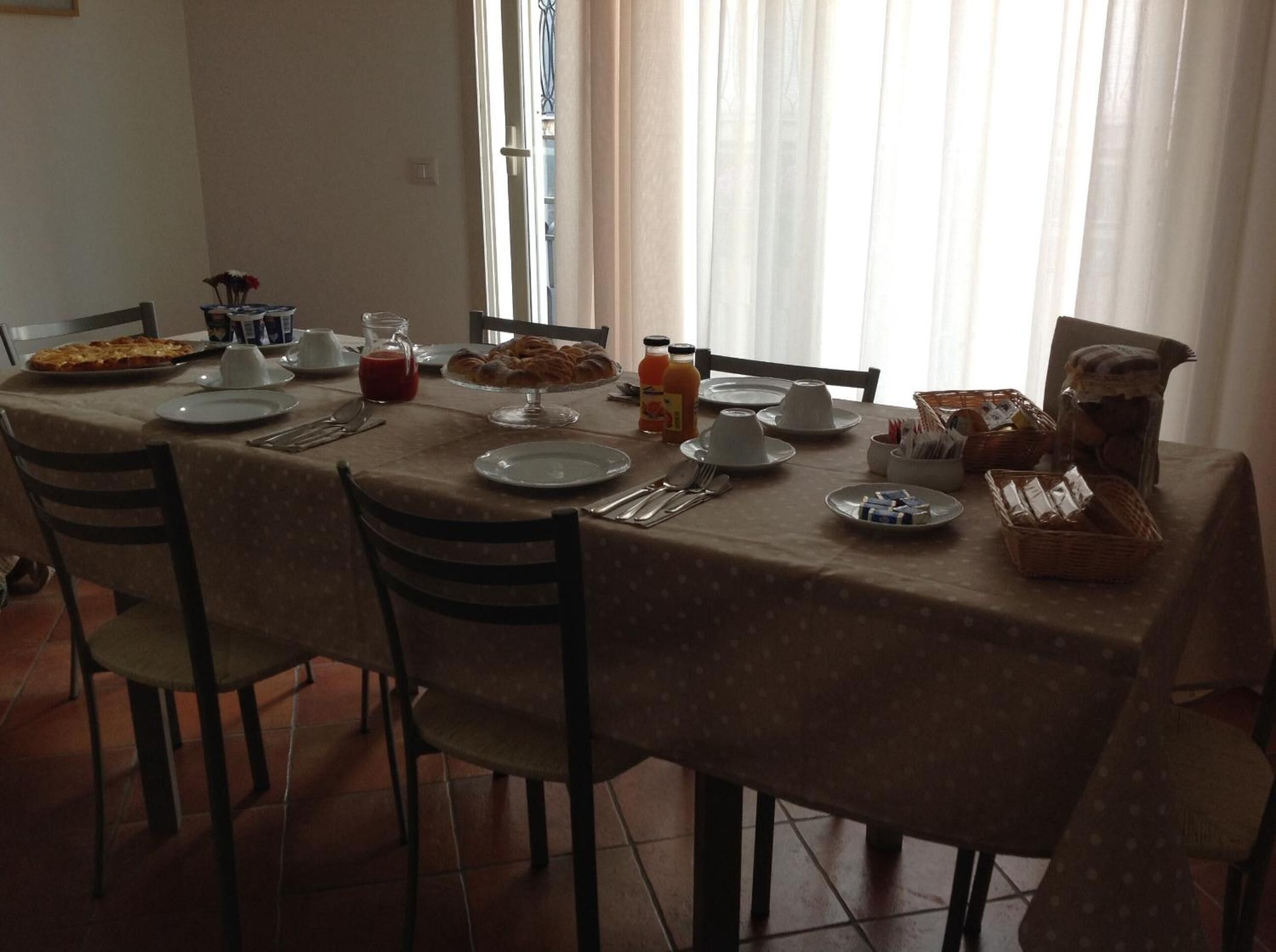 A dining table set for breakfast with plates, cups, and various food items.