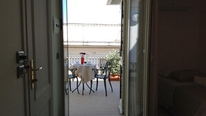 An open door leading to a balcony with a table and chairs, a potted plant, and a white fence in the background. - A Casa Di Amici (Giardini Naxos)