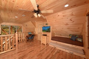 Cozy cabin with a bed, desk, and TV, offering a view of the outdoors.