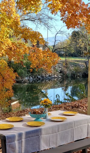 Ein Esstisch draußen mit Blick auf einen Teich und Herbstlaub.