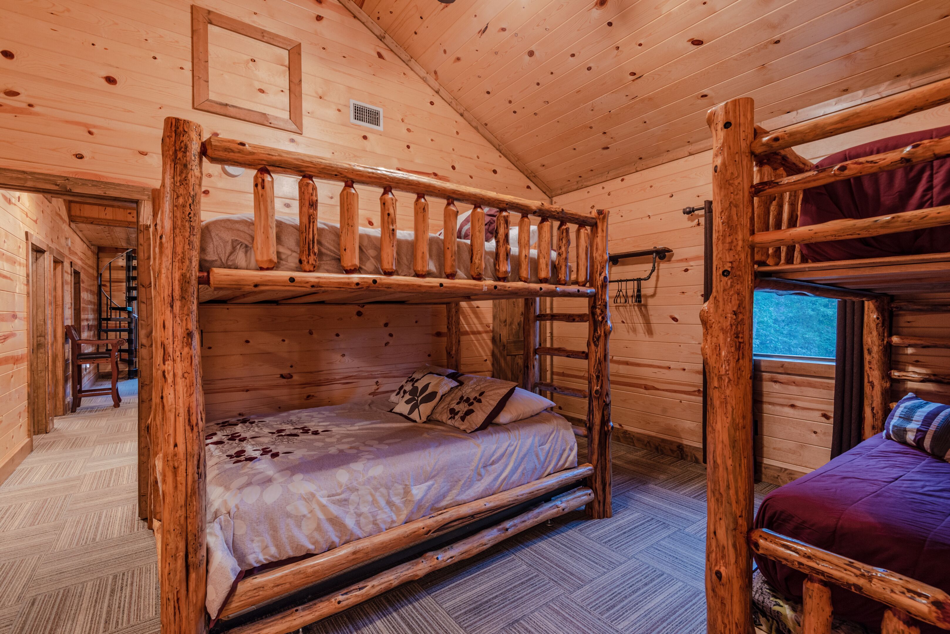 A wooden cabin room with a bunk bed, a small desk, and a chair.
