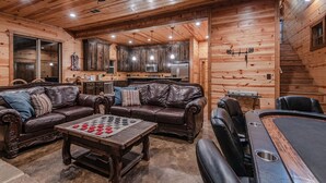 A cozy log cabin interior with a living room, a dining area, and a kitchen.