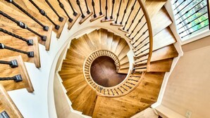 A spiral staircase with wooden steps and black balusters, leading to an upper floor. - Short Walk to Beach • Pool • Pets Allowed • (Miramar Beach)