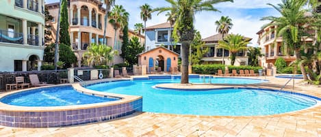 A resort pool area with multiple pools, lounge chairs, and palm trees.