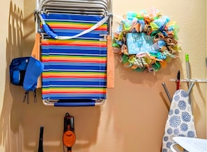 A striped towel rack, a colorful towel wreath, and a blue backpack on a wall.