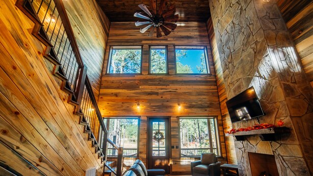 A log cabin interior with a fireplace, wooden walls, and a stone accent wall.