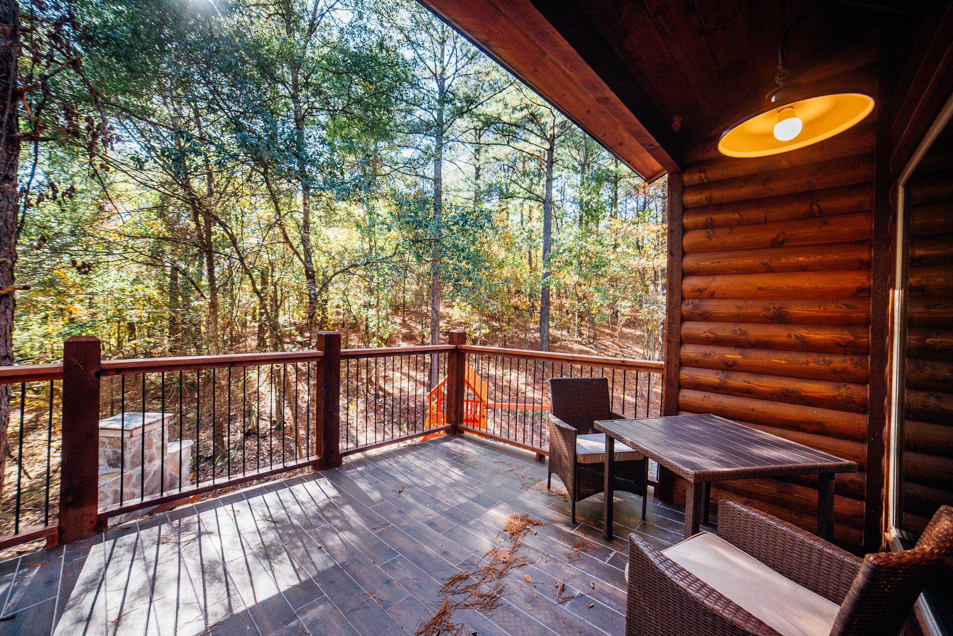 A wooden deck with a table and chairs, overlooking a forested area.