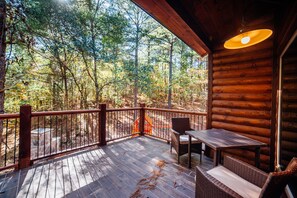 Eine Holzterrasse mit Tisch und Stühlen mit Blick auf ein bewaldetes Gebiet.