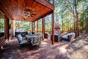 Eine Holzterrasse mit Gartenmöbeln und einem Kamin aus Stein.
