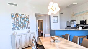 A modern kitchen with a dining area, featuring a large wooden table, black chairs, and a decorative bowl.
