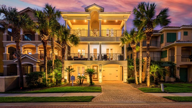 A multi-story hotel with a central courtyard, balconies, and palm trees.