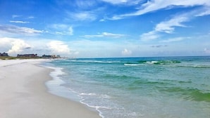 A beach with clear blue water and a sandy shore.