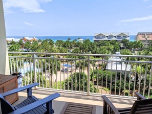 A balcony with a view of a beach and resort buildings.