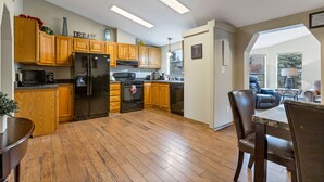 Une cuisine dotée de meubles en bois, d’un réfrigérateur, d’une cuisinière et d’un coin repas avec une table et des chaises.
